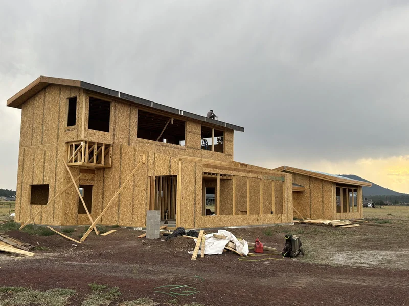 Framing progress with a crew member working the roofline
