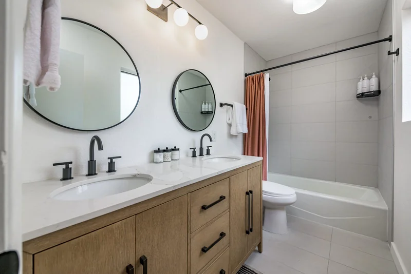 Remodeled bathroom with double vanity and tub and shower combo