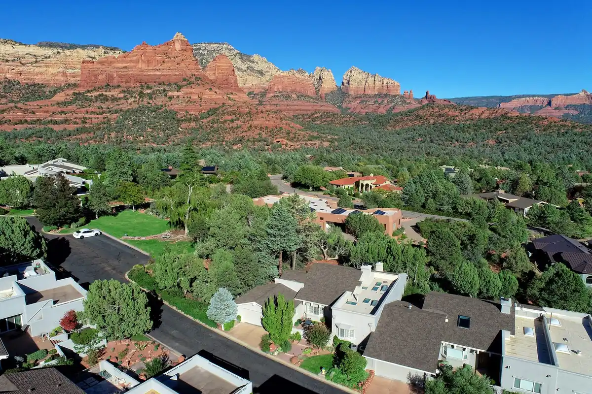 Aerial view of a Sedona neighborhood with red rock formations rising behind the homes
