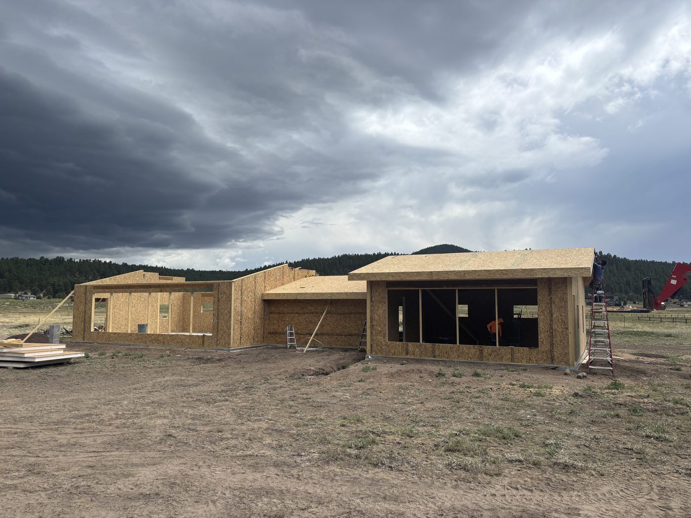 Custom home under construction in Flagstaff, framing stage with storm clouds overhead