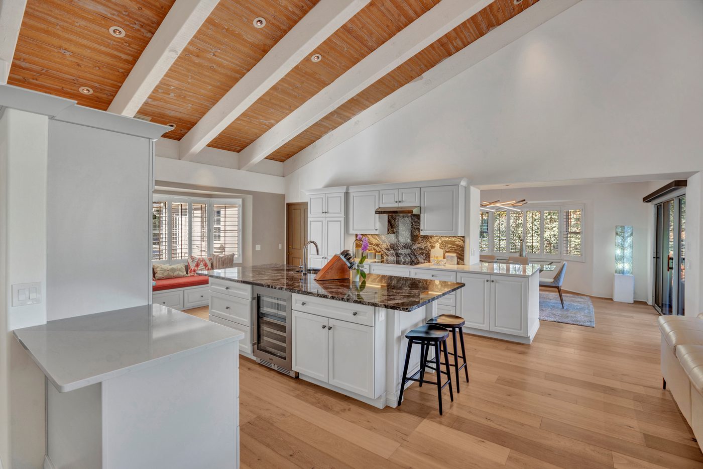 Finished kitchen remodel with white cabinetry, stone island, and open living area