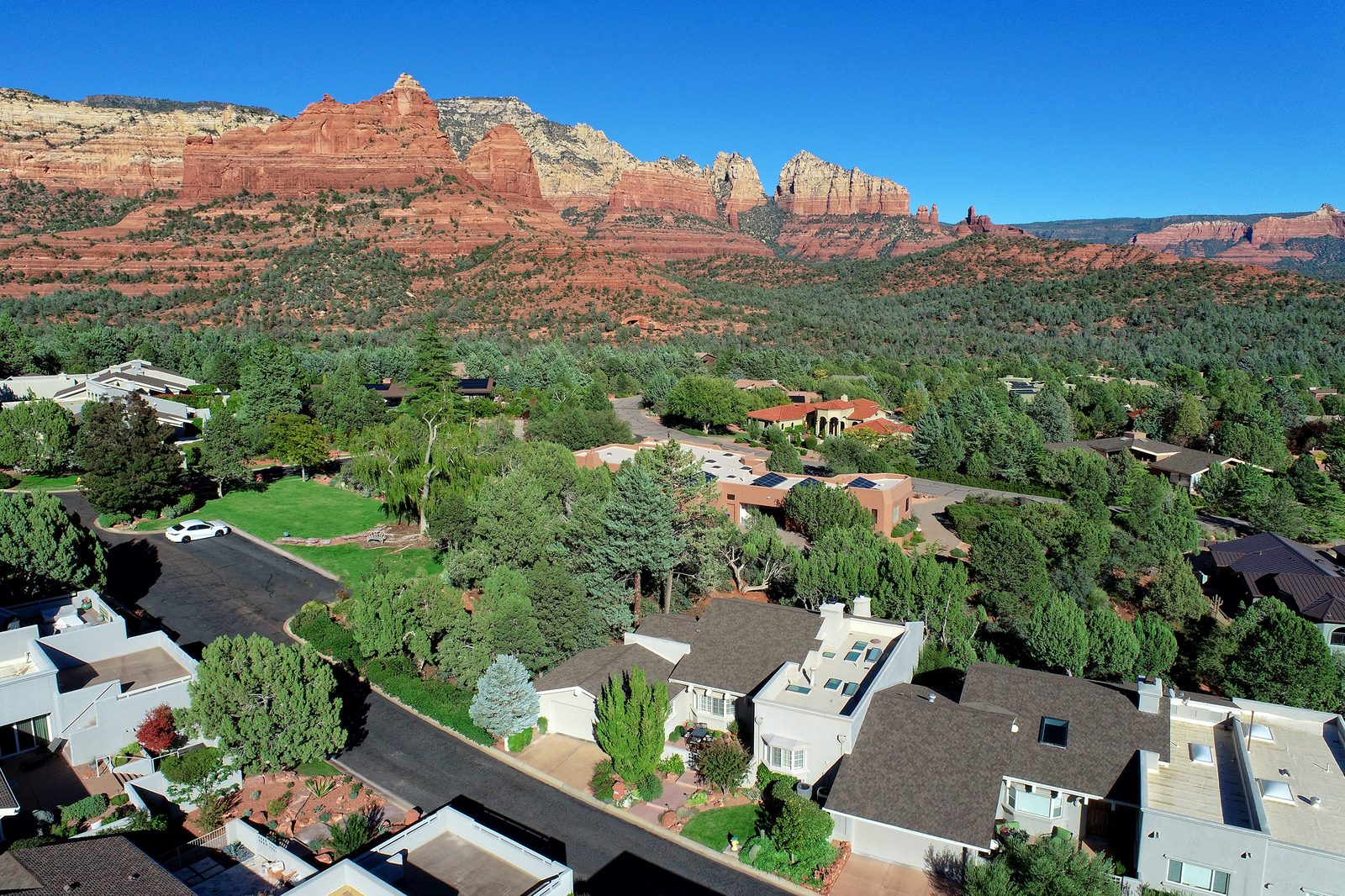 Aerial view of a Sedona neighborhood with red rock formations rising behind the homes